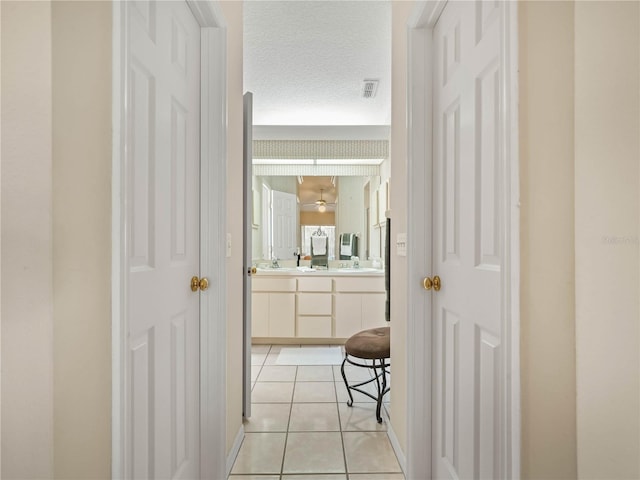 hallway with a sink, light tile patterned floors, and a textured ceiling