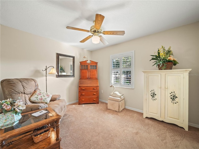 sitting room with a ceiling fan, light carpet, a textured ceiling, and baseboards