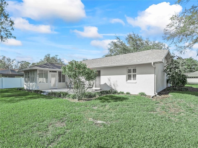 back of property with a lawn, a patio, a sunroom, fence, and stucco siding