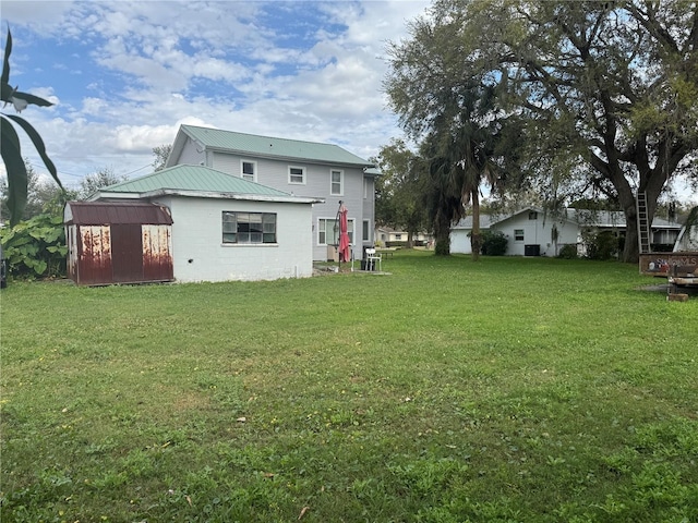 back of property with an outbuilding, a shed, a lawn, and concrete block siding