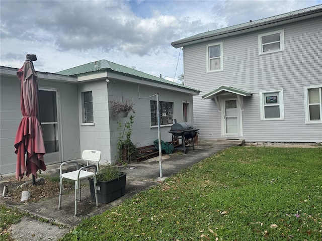 back of house featuring metal roof and a yard