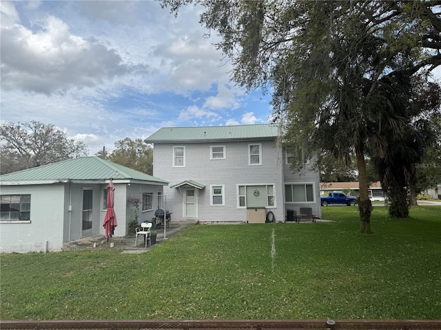 rear view of house with metal roof and a yard