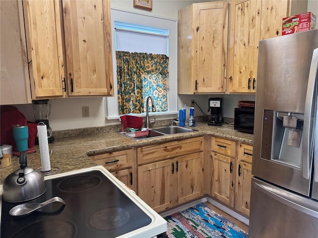 kitchen with white electric range, stainless steel refrigerator with ice dispenser, a sink, and light stone countertops