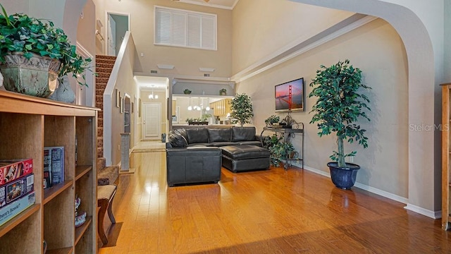 interior space featuring arched walkways, baseboards, a high ceiling, and wood finished floors