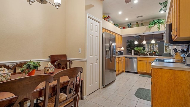 kitchen featuring appliances with stainless steel finishes, light countertops, decorative light fixtures, and light tile patterned flooring