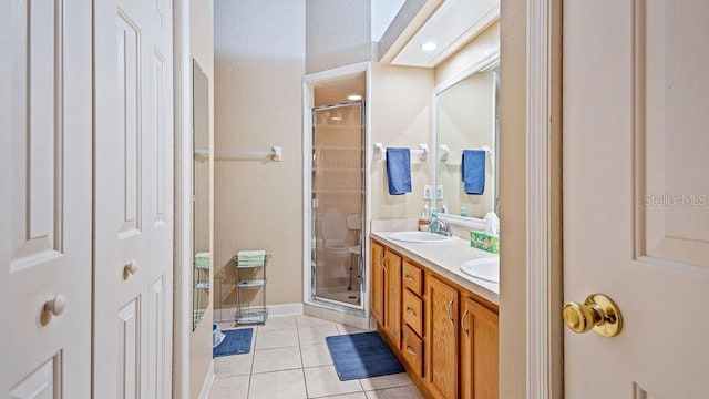 full bath with double vanity, a closet, a sink, a shower stall, and tile patterned floors