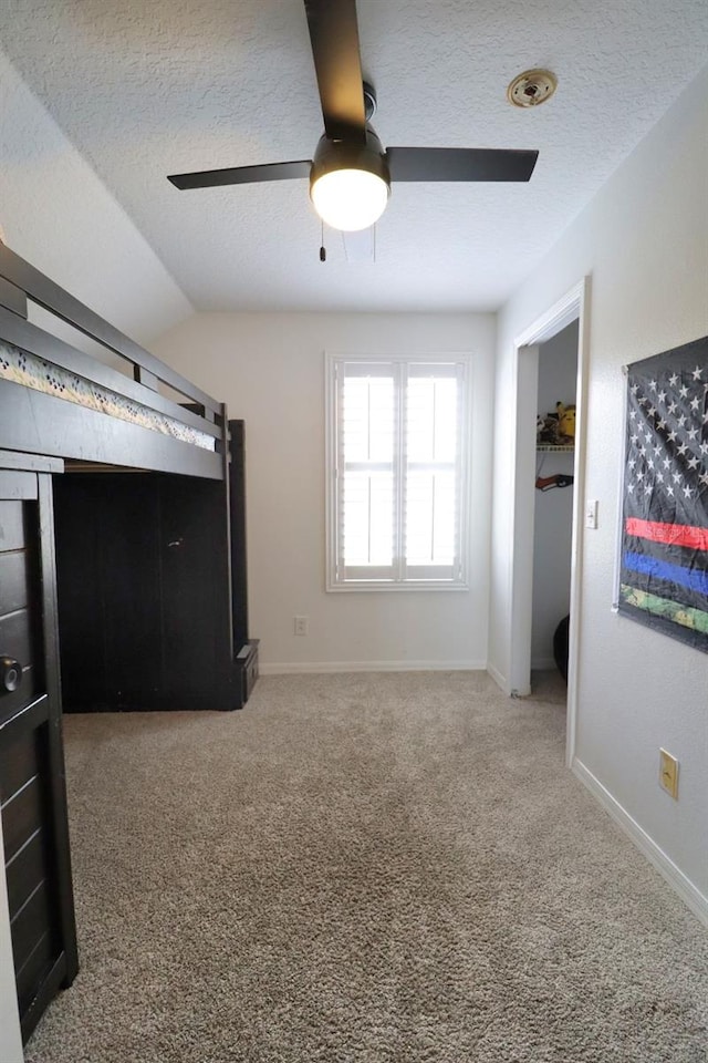 unfurnished bedroom with carpet floors, baseboards, vaulted ceiling, and a textured ceiling