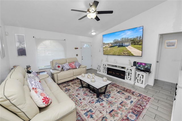 living area featuring lofted ceiling, ceiling fan, wood tiled floor, and a glass covered fireplace