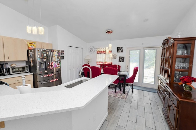 kitchen with hanging light fixtures, stainless steel refrigerator with ice dispenser, a sink, and light countertops