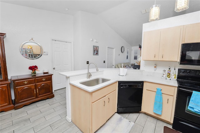 kitchen with a peninsula, a sink, light countertops, black appliances, and pendant lighting