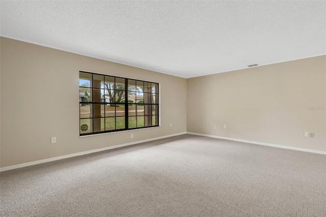 carpeted spare room with visible vents, a textured ceiling, and baseboards