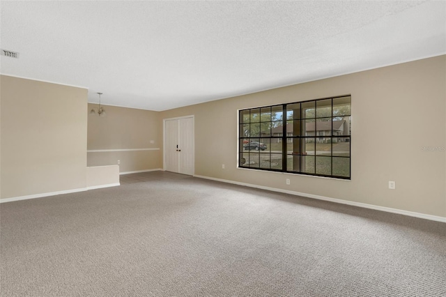 carpeted spare room featuring visible vents, baseboards, a chandelier, and a textured ceiling