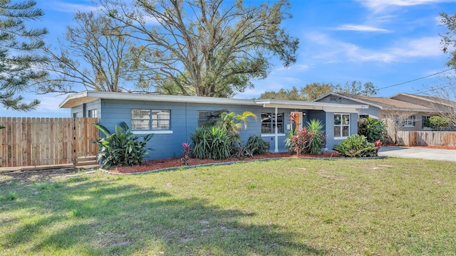 single story home with driveway, fence, and a front yard