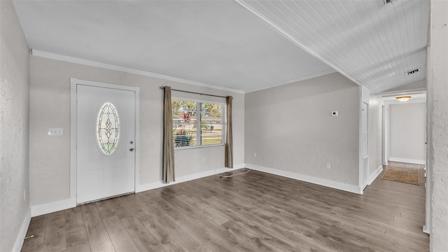 foyer featuring lofted ceiling, crown molding, baseboards, and wood finished floors