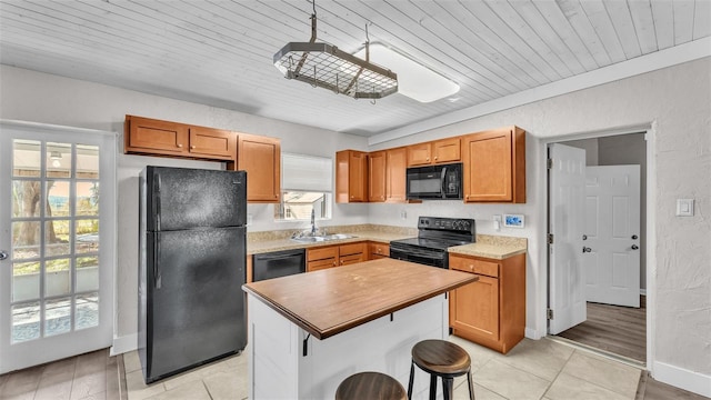 kitchen featuring a kitchen island, brown cabinets, black appliances, a kitchen bar, and a sink