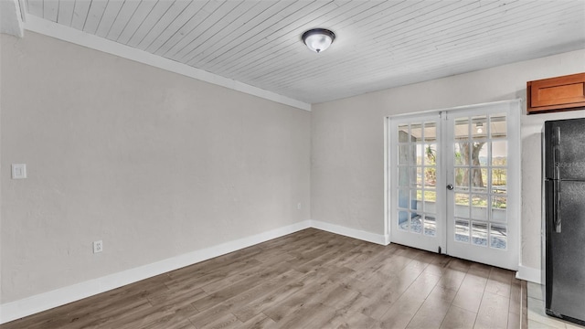 empty room featuring french doors, wooden ceiling, light wood-style flooring, and baseboards