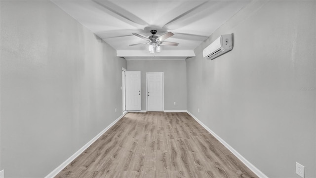 spare room with ceiling fan, a wall unit AC, light wood-style flooring, and baseboards