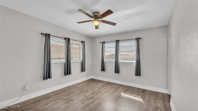 spare room with ceiling fan, wood finished floors, and baseboards