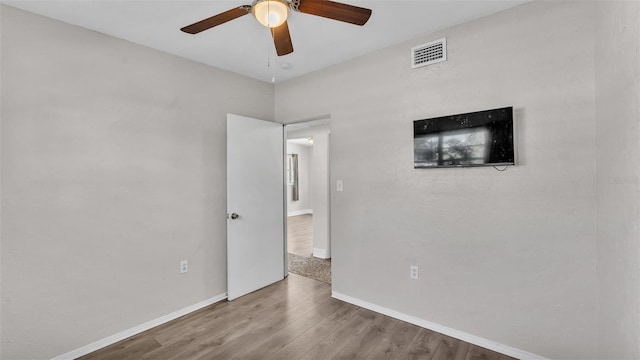 unfurnished bedroom featuring ceiling fan, wood finished floors, visible vents, and baseboards