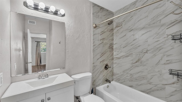 bathroom featuring visible vents, a textured wall, toilet, tub / shower combination, and vanity