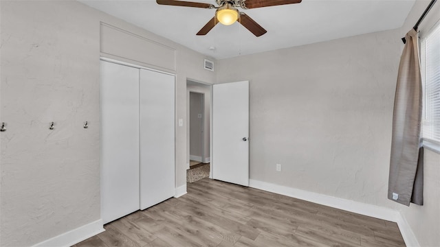 unfurnished bedroom featuring ceiling fan, visible vents, baseboards, a closet, and light wood finished floors