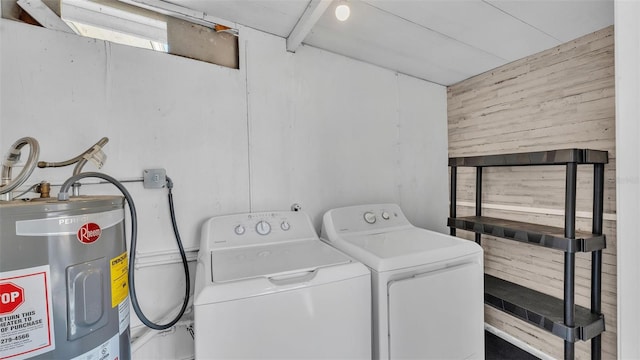 clothes washing area featuring laundry area, water heater, independent washer and dryer, and wood walls