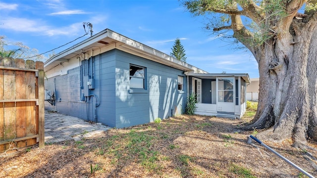 view of property exterior featuring a sunroom, fence, and a patio