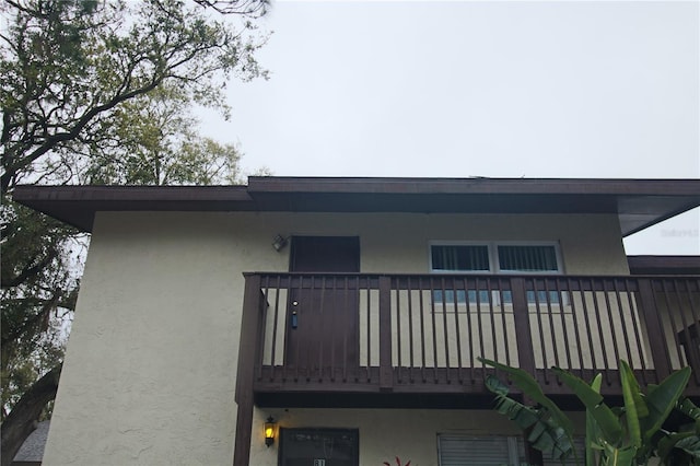 back of house with a balcony and stucco siding