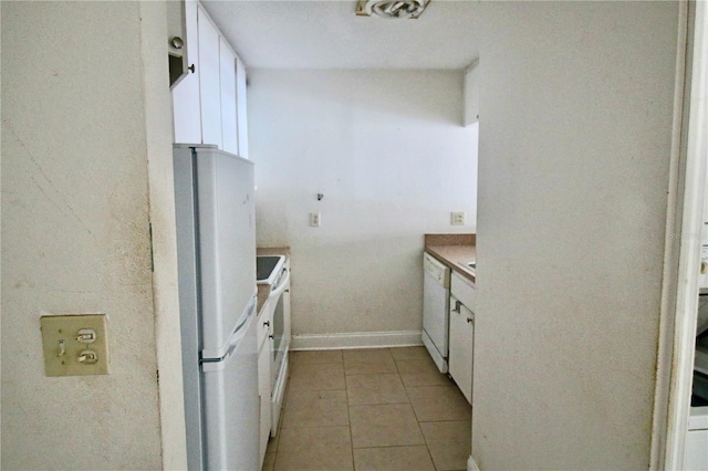 kitchen featuring white appliances, light tile patterned floors, baseboards, light countertops, and white cabinets