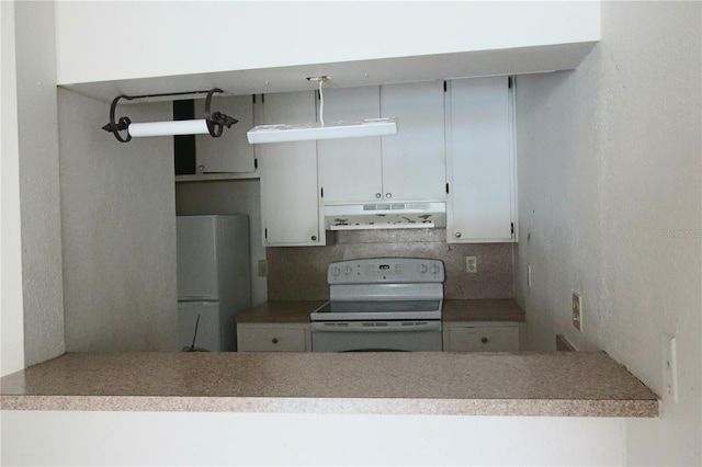 kitchen with white appliances, a peninsula, decorative backsplash, white cabinets, and under cabinet range hood