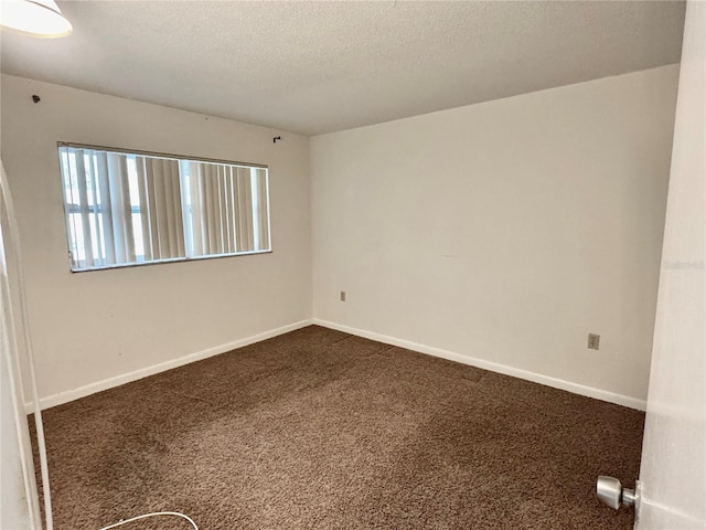 unfurnished room featuring baseboards, dark carpet, and a textured ceiling