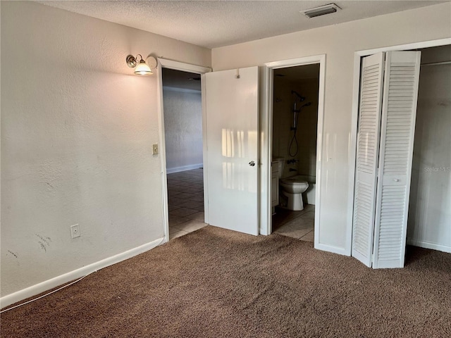 unfurnished bedroom featuring tile patterned floors, visible vents, a textured ceiling, and carpet floors