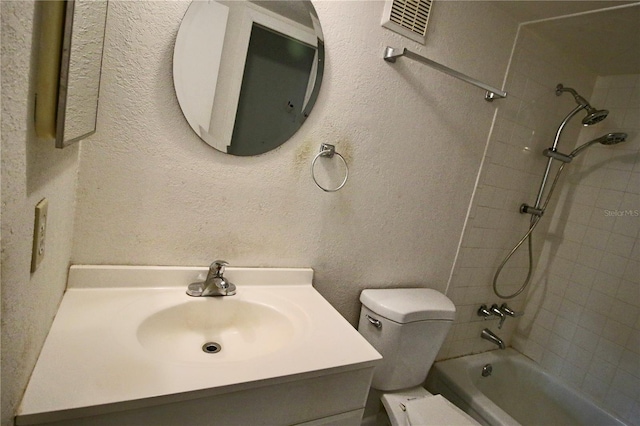 full bath with visible vents, toilet, bathing tub / shower combination, a textured wall, and vanity