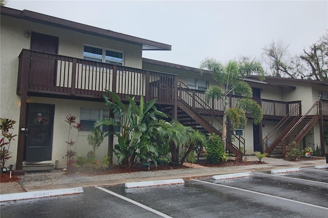 view of property featuring stairway and uncovered parking