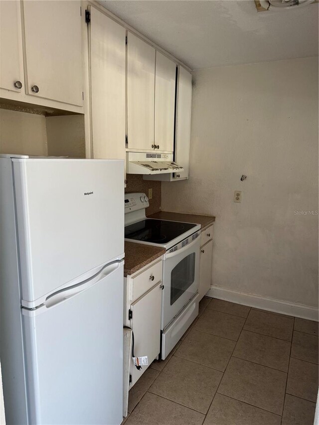 141 Fernery Rd Unit B5, Lakeland, FL 33809 - kitchen featuring light tile patterned flooring, dark countertops, baseboards, white appliances, and under cabinet range hood