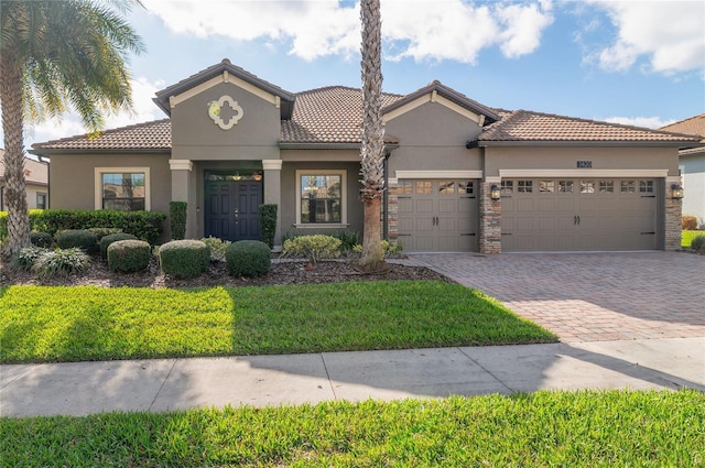 mediterranean / spanish-style home featuring a garage, a tiled roof, decorative driveway, and stucco siding