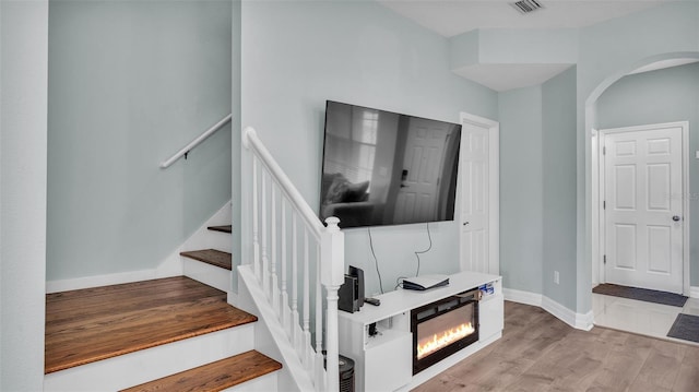 staircase with visible vents, baseboards, arched walkways, and wood finished floors