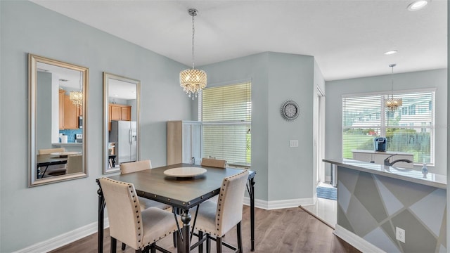 dining space with light wood-type flooring, recessed lighting, baseboards, and an inviting chandelier