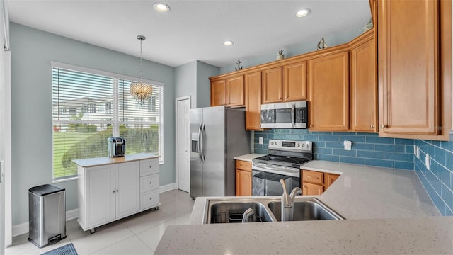 kitchen with appliances with stainless steel finishes, decorative light fixtures, a sink, and backsplash