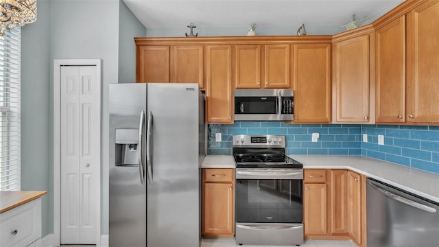 kitchen with appliances with stainless steel finishes, light countertops, and decorative backsplash