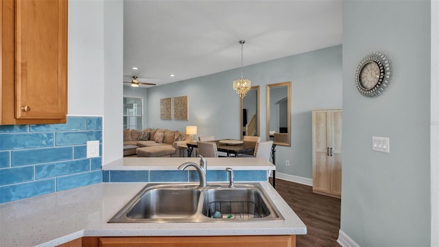 kitchen featuring a sink, open floor plan, light countertops, backsplash, and decorative light fixtures