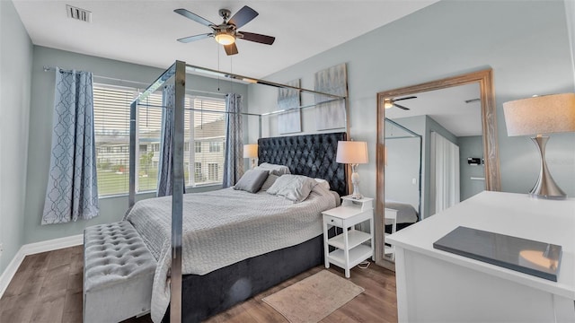 bedroom with baseboards, visible vents, ceiling fan, and wood finished floors