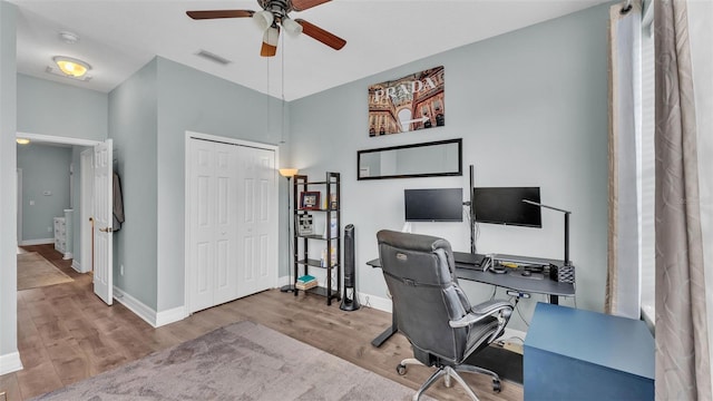 home office featuring light wood finished floors, baseboards, visible vents, and ceiling fan