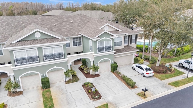 view of front of property with roof with shingles, driveway, an attached garage, and stucco siding