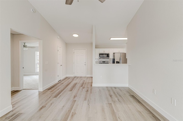 interior space featuring ceiling fan, baseboards, and light wood-style flooring