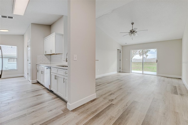 kitchen with visible vents, white cabinets, dishwasher, open floor plan, and light countertops