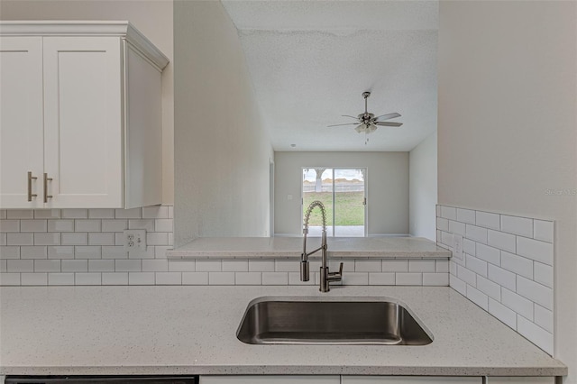 kitchen featuring light stone countertops, tasteful backsplash, white cabinetry, and a sink