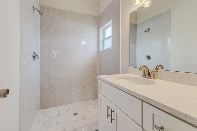 full bathroom featuring a tile shower and vanity