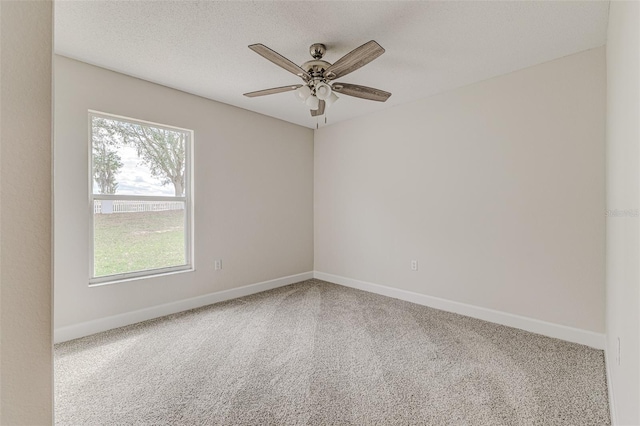 unfurnished room featuring a textured ceiling, carpet, a ceiling fan, and baseboards