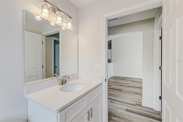 bathroom featuring visible vents, vanity, baseboards, and wood finished floors